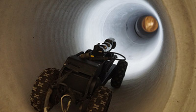 A robot with camera and wheels moving through a pipe for NDT